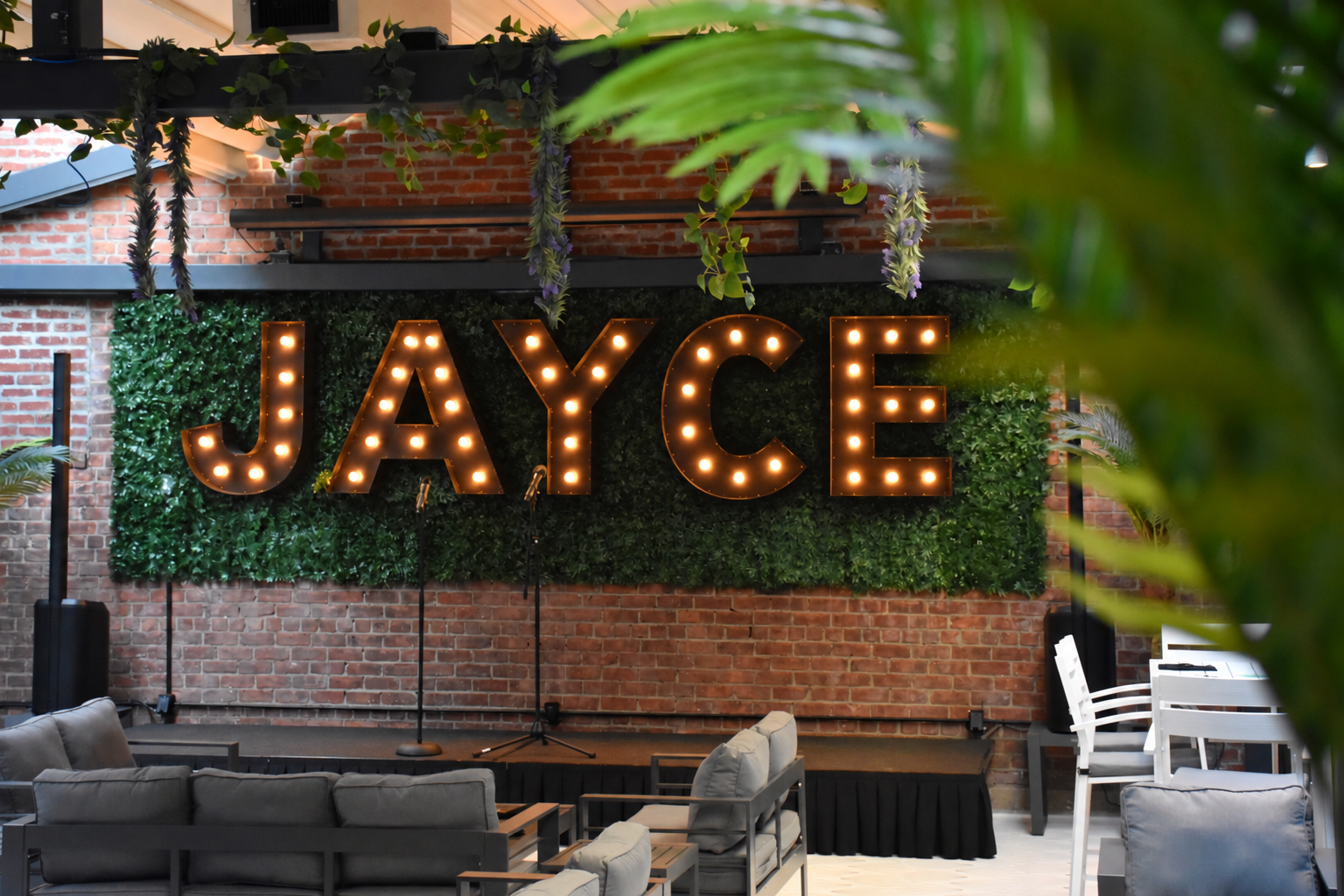 Jayce marquee sign glowing against the green hedge wall